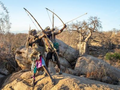 Lake Eyasi, Tanzania, 11th September 2019: Hadzabe men on a rock with his bow and arrows
